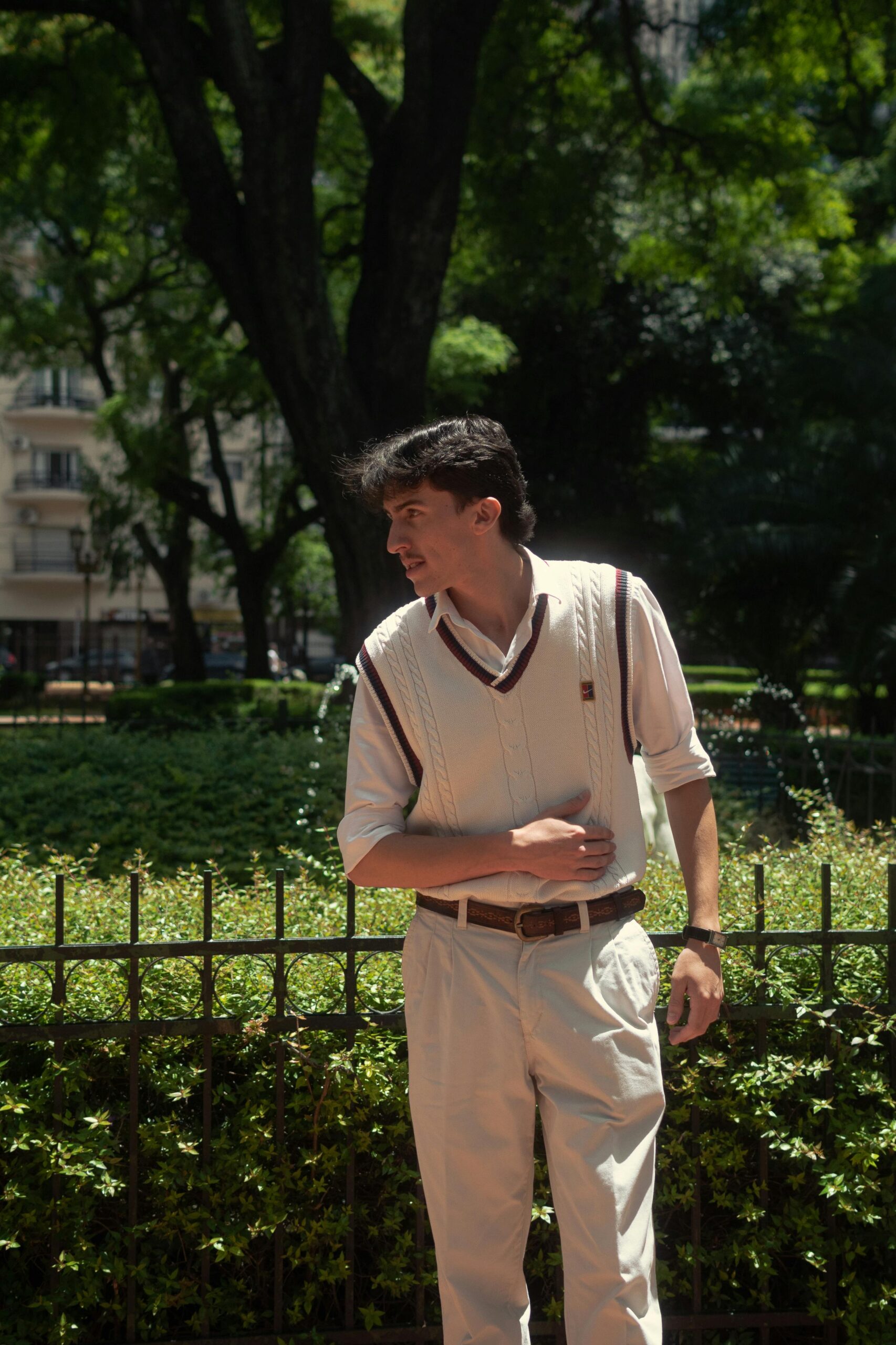 Portrait of a stylish young man standing confidently in a sunny Buenos Aires park.